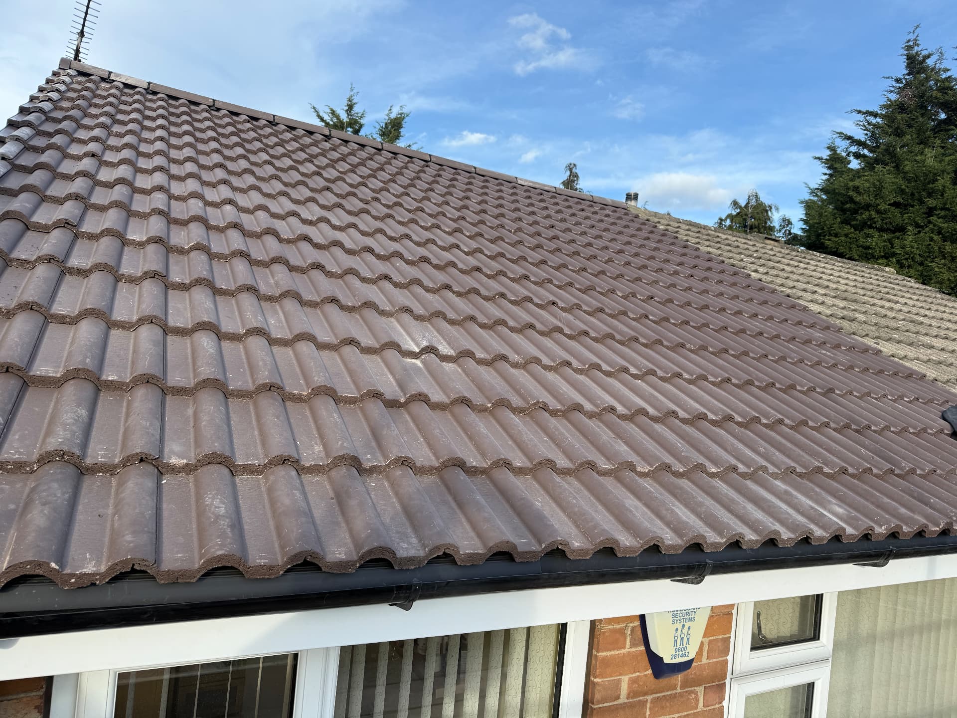 Brown tiled roof with new black guttering