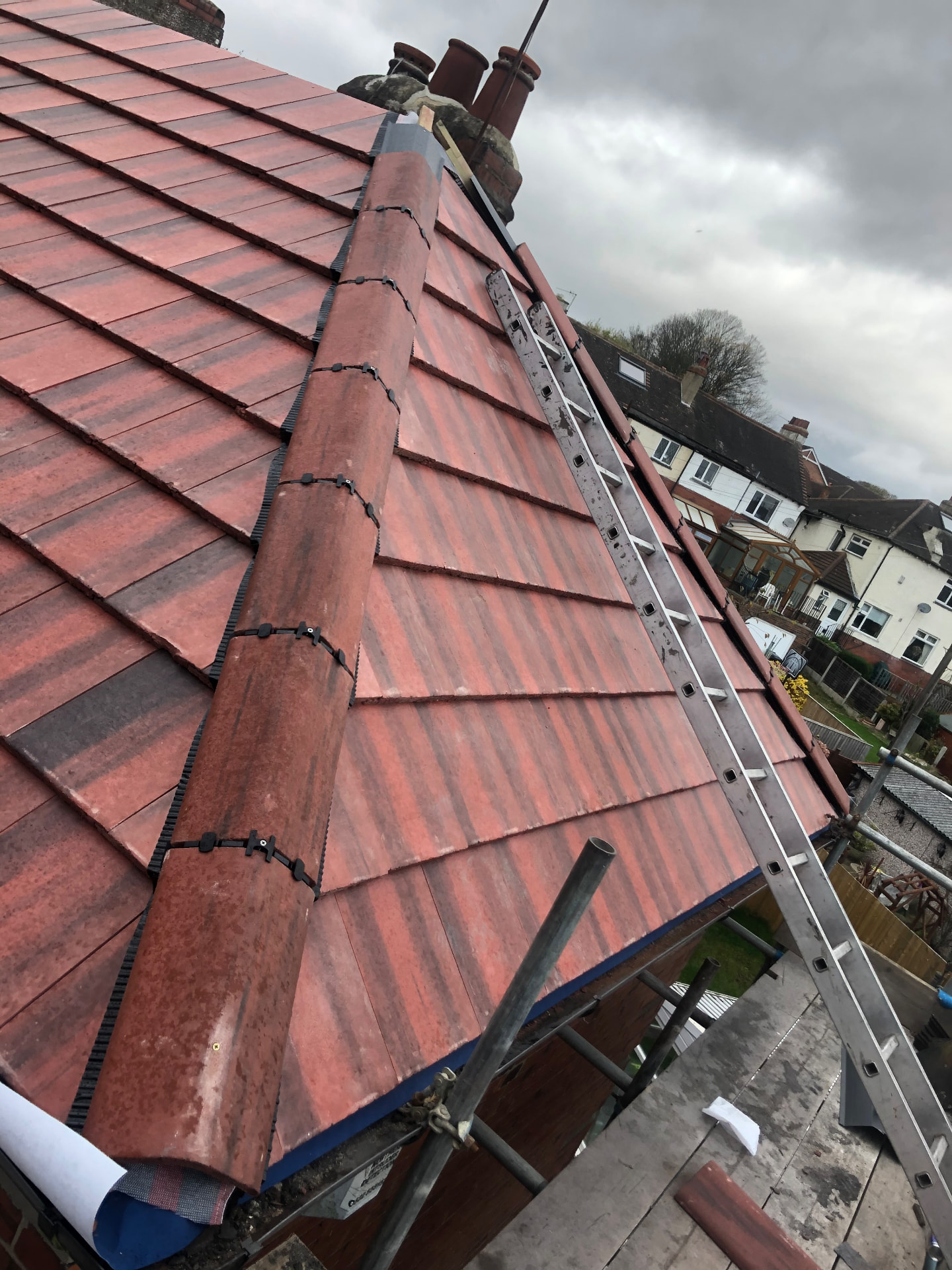New ridge tiles and lead flashing on a red tiled roof